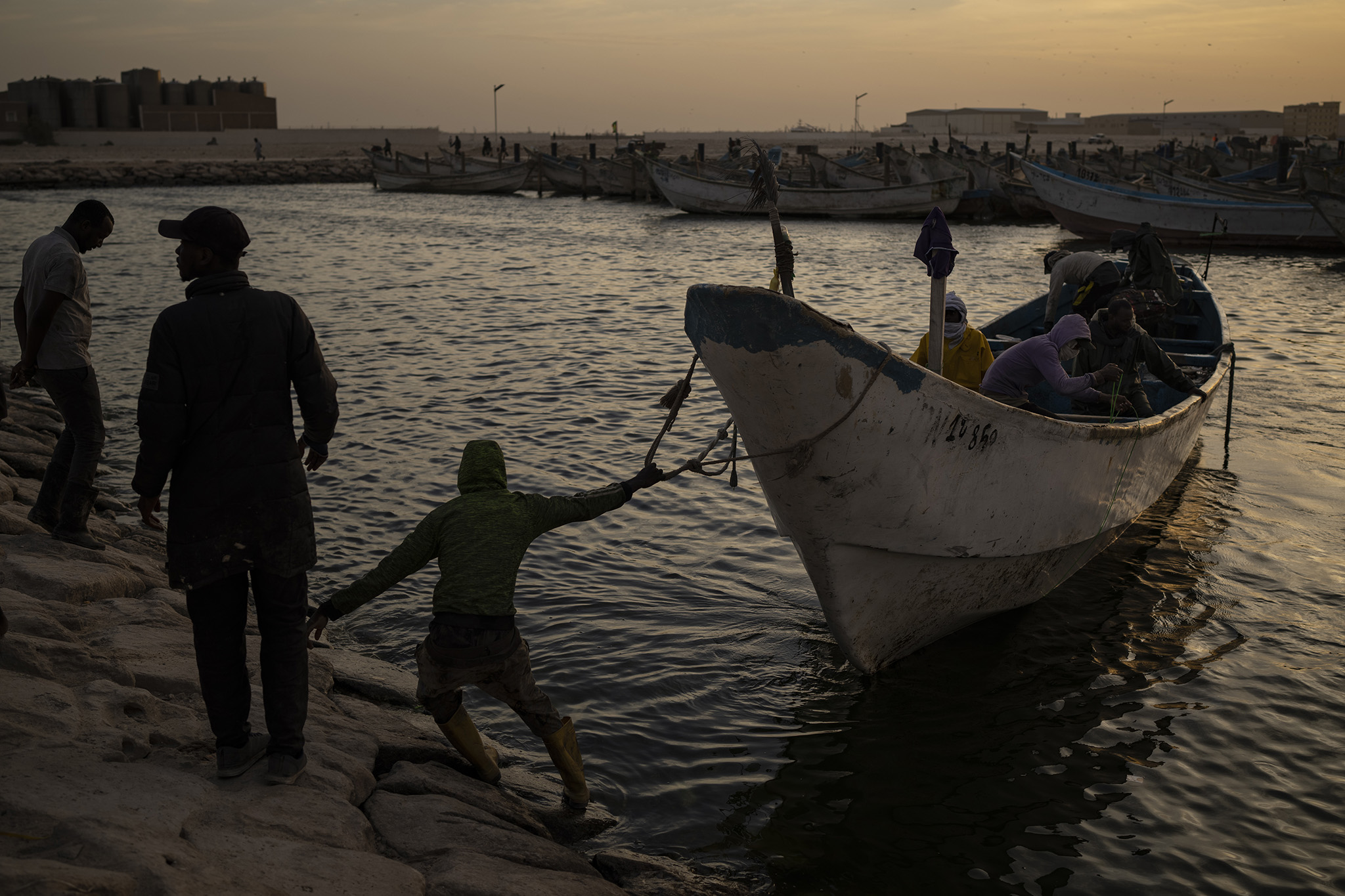 Men prepare to dock a fishing boat at the port in Nouadhibou, Mauritania, on November 27, 2021. Strategic support for the Sahel should spur investment and economic growth. (Photo by Felipe Dana/AP)