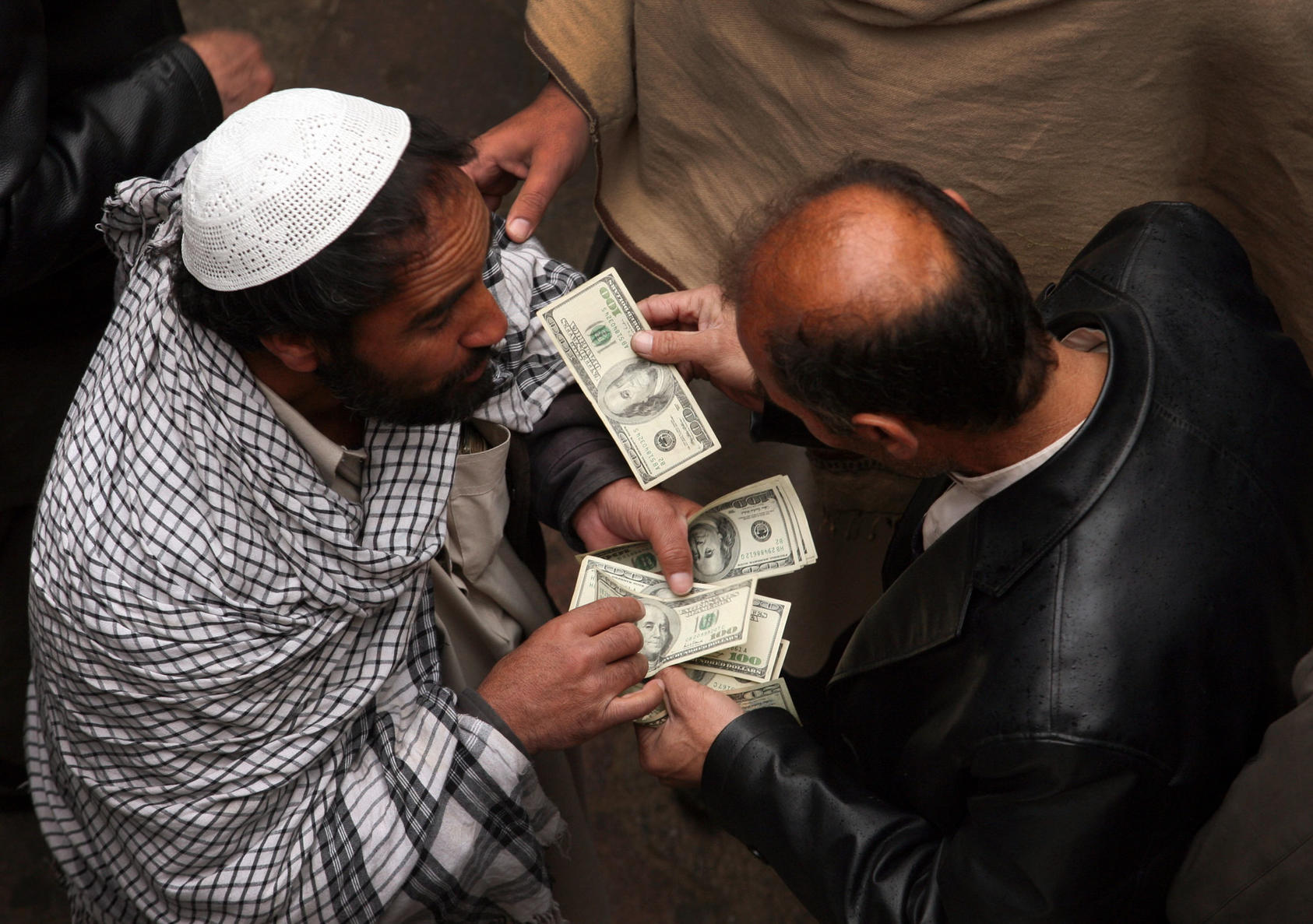 Men negotiate money exchanges at a market in Kabul, on Jan. 29, 2011. The large, informal, market is crucial to the economy in a country where many of the poor do not use banks. Potential losses of as much as $900 million at the Kabul Bank could deepen distrust of banks in the country. (Michael Kamber/The New York Times) 