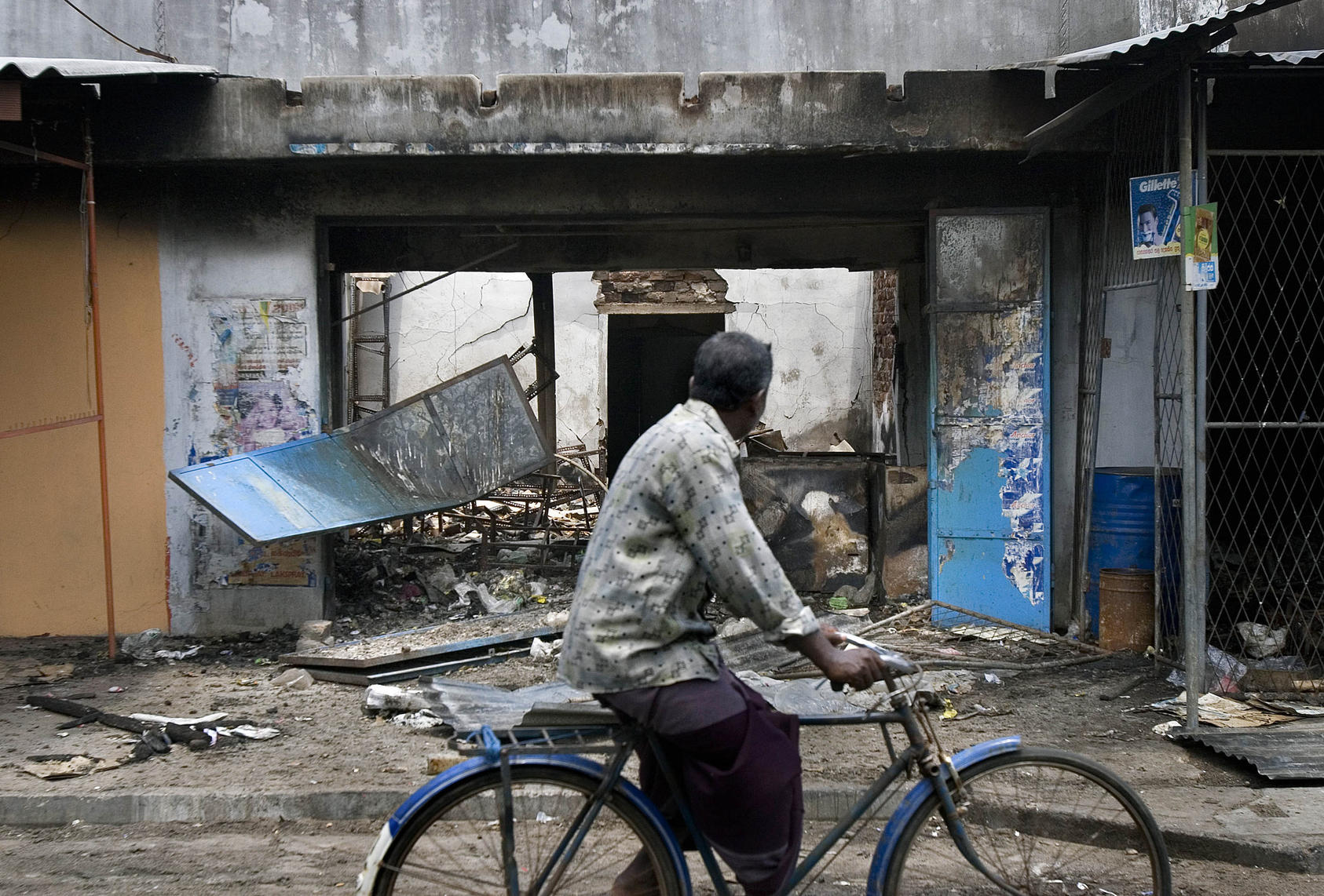 A man bicycles on May 7th, 2006, past Tamil-owned stores that were set ablaze by a Sinhalese mob in Trincomalee, Sri Lanka. April was the bloodiest month since the government and the separatist Liberation Tigers of Tamil Eelam signed a cease-fire in February 2002 that was supposed to end nearly two decades of killing here. 