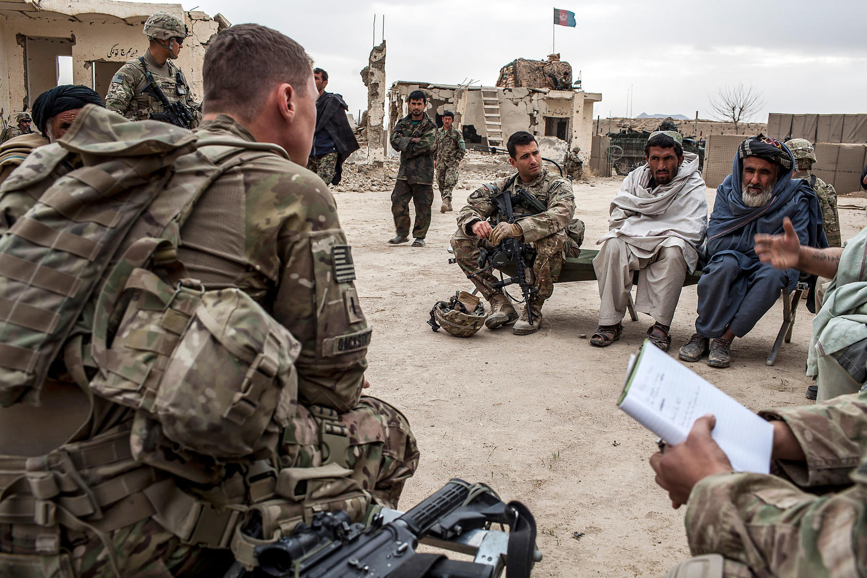 U.S. Army Capt. Aaron Daniele sits next to elders from the village of Tieranon in Pashmul, Afghanistan, in an effort to establish an Afghan Local Police unit in their village