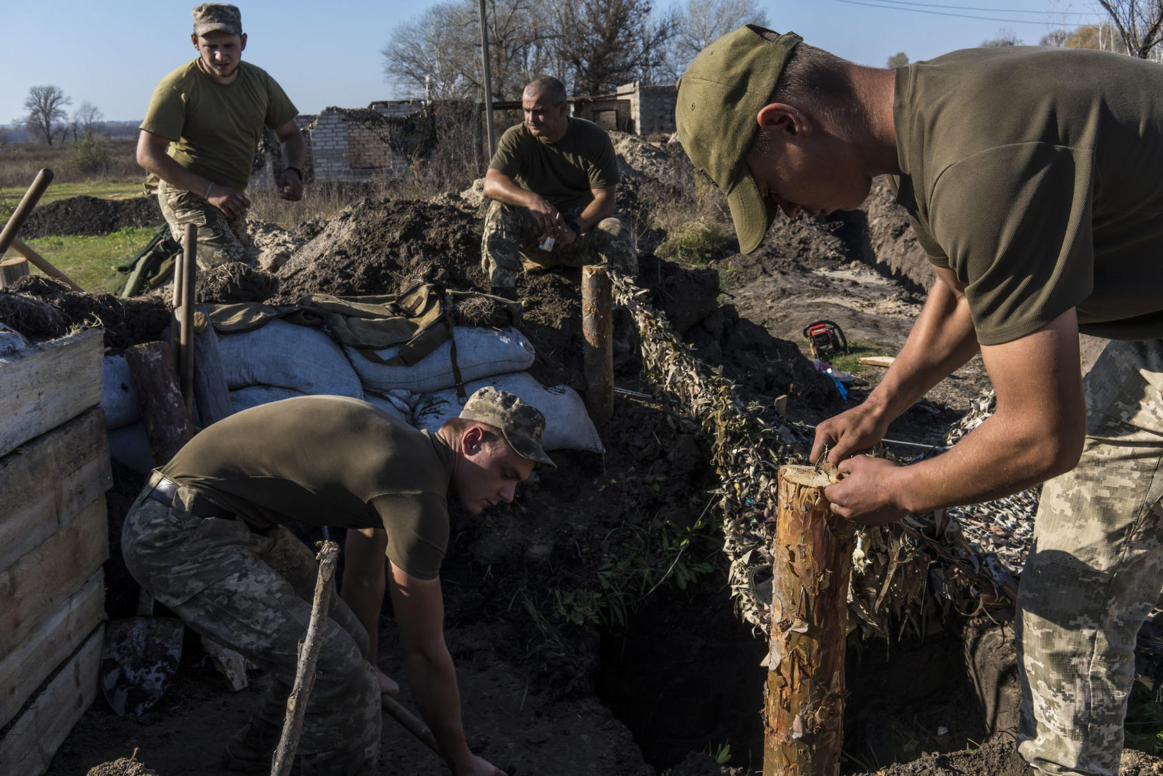Ukrainian troops dig bunkers after withdrawing about 500 yards from the front line in the village of Stanytsia Luhanska. The pullback by both sides helped prepare for December 9 peace talks in the Russia-Ukraine war. (Brendan Hoffman/The New York Times)