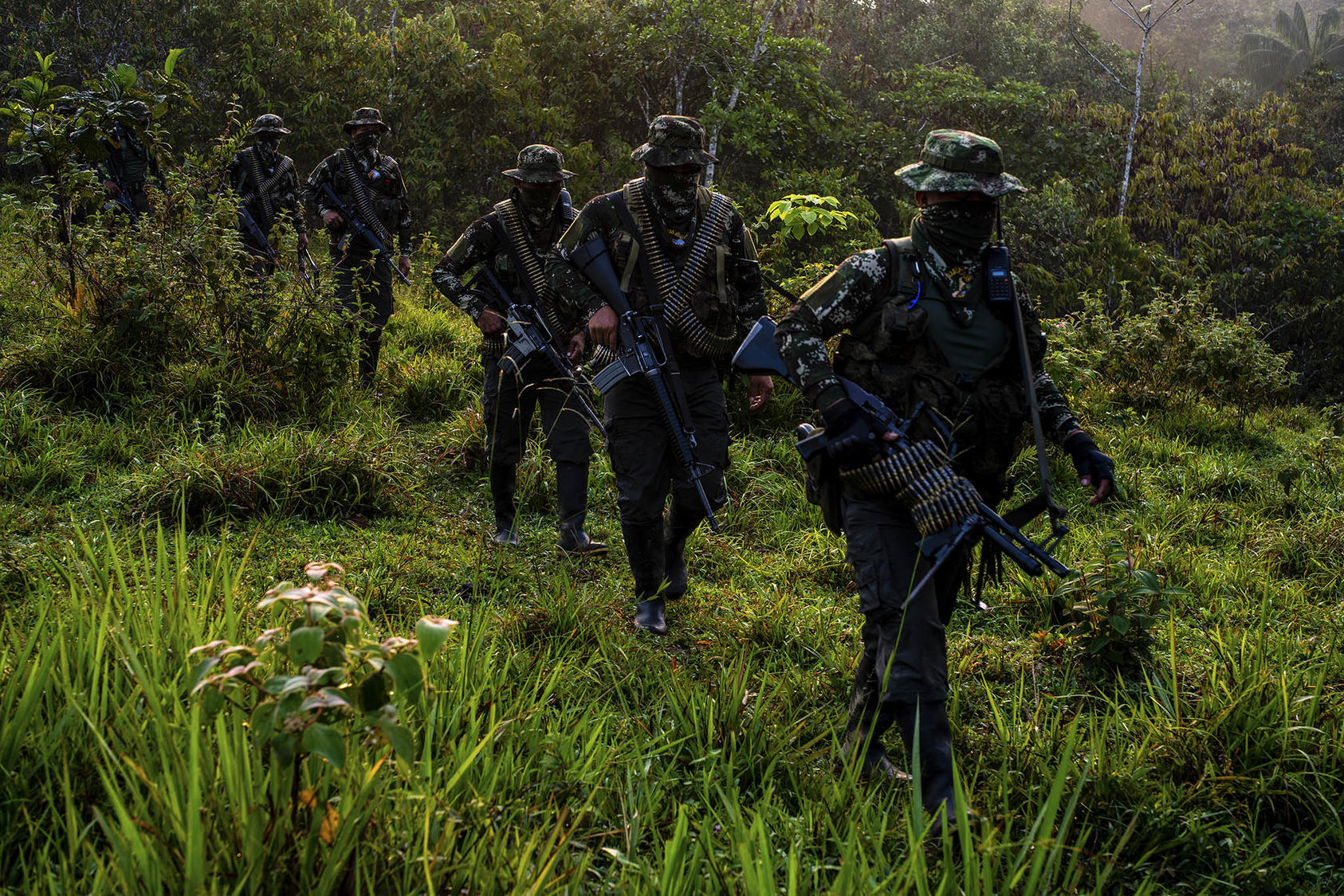 Combatientes enmascarados de una milicia llamada Comando de Frontera se desplazan por terreno selvático el año pasado. El grupo rechazó el acuerdo de paz de 2016 y según los informes, trafica drogas a lo largo de la frontera sur de Colombia. (Federico Ríos/The New York Times)