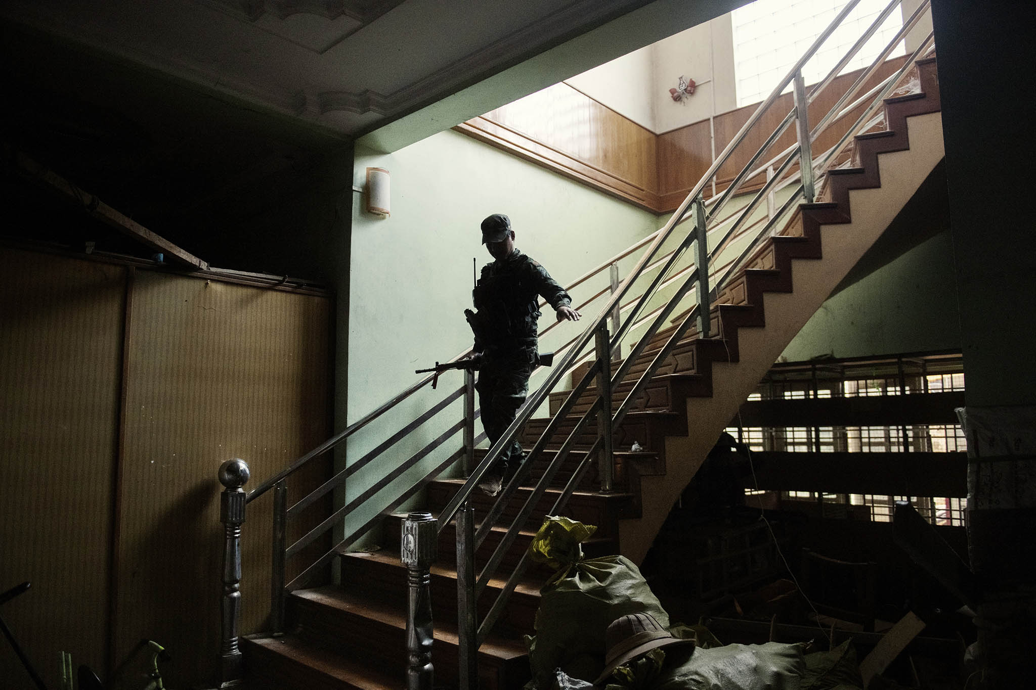 A rebel soldier patrols an abandoned house in Loikaw, Myanmar. Januart 31, 2024. (Adam Ferguson/The New York Times)]