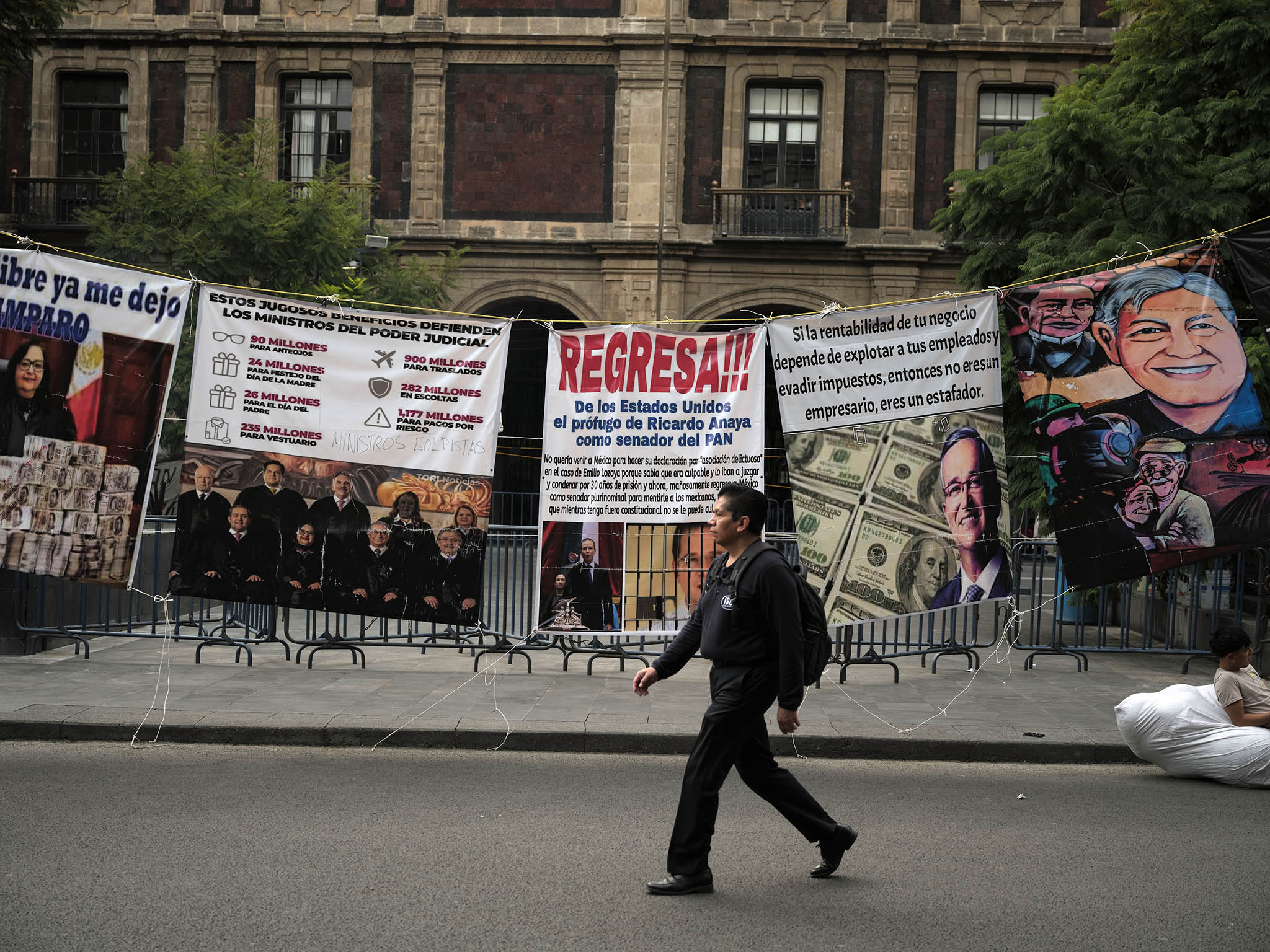 A pedestrian walks in front of protest signs outside Mexico’s Supreme Court building in Mexico City on November 1, 2024. Judicial reform, which went into effect on September 15, allows voters to elect judges. (Alejandro Cegarra/The New York Times)