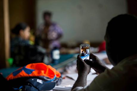 An audience member takes a photo of a community leader speaking during a family violence prevention workshop in the Autonomous Region of Bougainville, Papua New Guinea. July 2, 2015. (U.S. Air Force)
