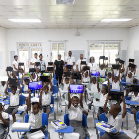 Dr. Deschamps and staff of the civic group GHESKIO join pupils who celebrate receiving tablet computers for their studies. Such Haitian civil society groups are strong partners with international peacebuilding efforts. (Haitian Global Health Alliance)