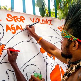 A man paints a sign at an event to raise awareness about preventing violence against women and girls in Papua New Guinea. (UN Women/Johaness Terra via Flickr CC BY-NC-ND 2.0)