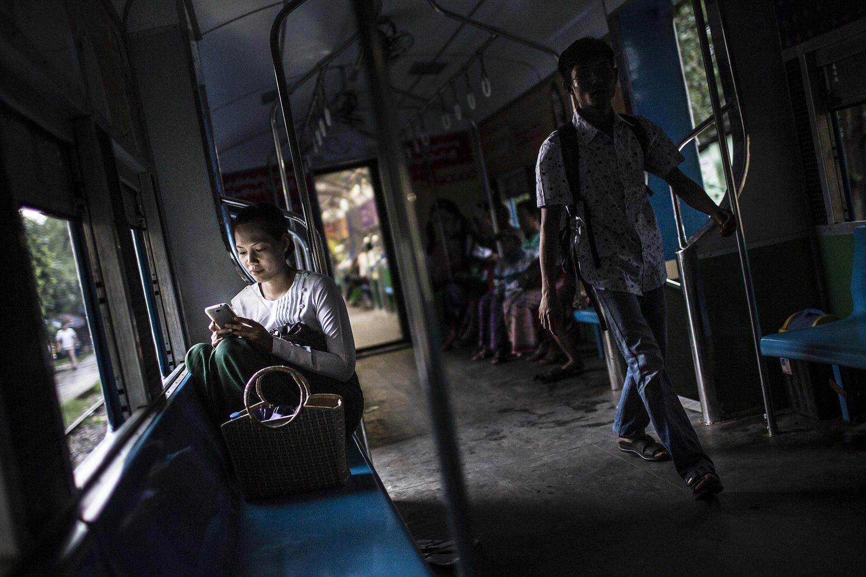 A woman uses her cell phone on the Circle Line train in Yangon, Myanmar, June 2014. (Mathieu Willcocks/The New York Times)