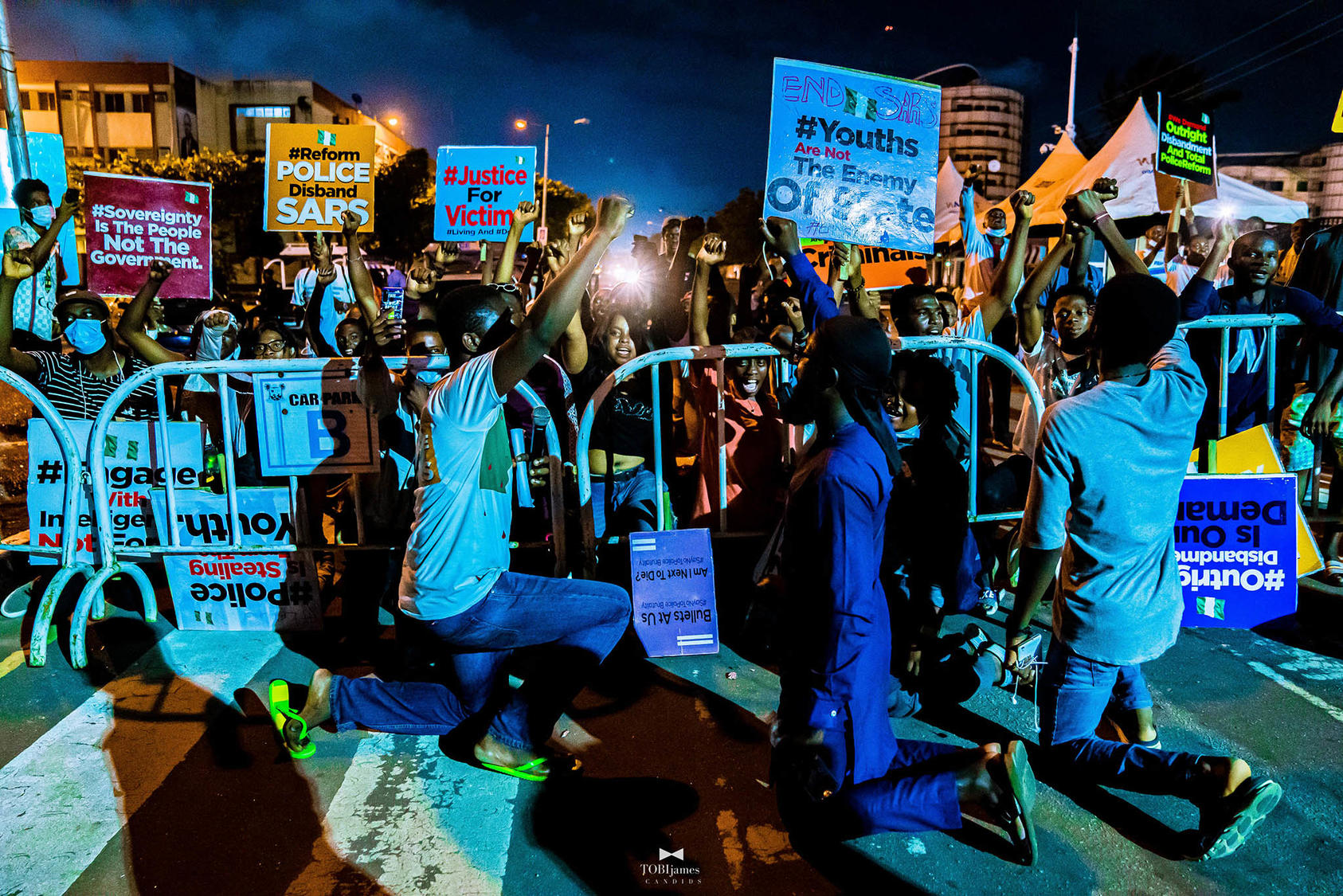 Nigerian youth kneel for the national anthem during one of many protests against police brutality this month. (TobiJamesCandids/CC License 4.0)