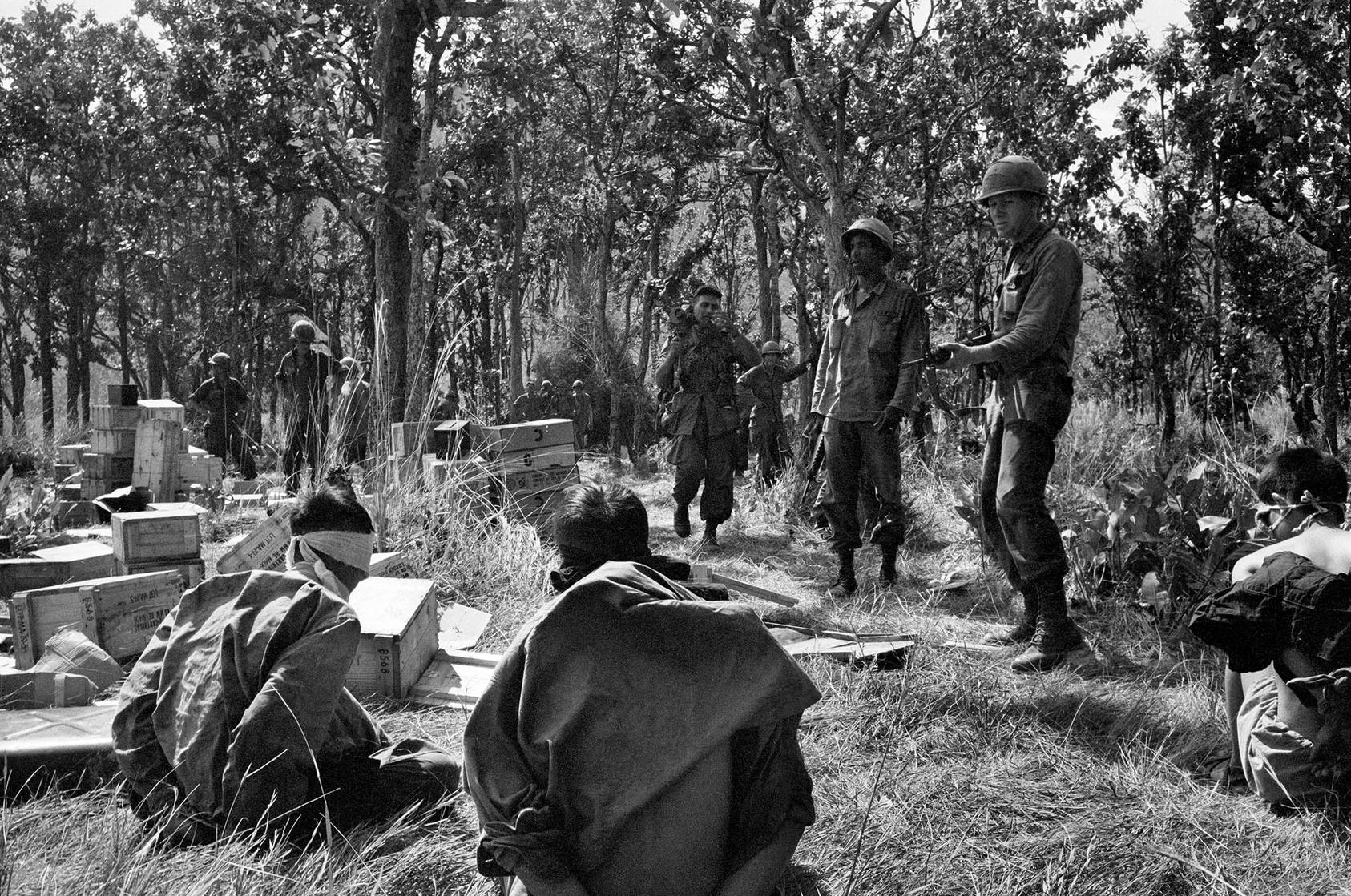 U.S. troops guard North Vietnamese prisoners in 1965, early in the Vietnam War. U.S. and Vietnamese veterans have led reconciliation work in decades since, notably in searching for remains of those killed in the war. (Neil Sheehan/The New York Times)