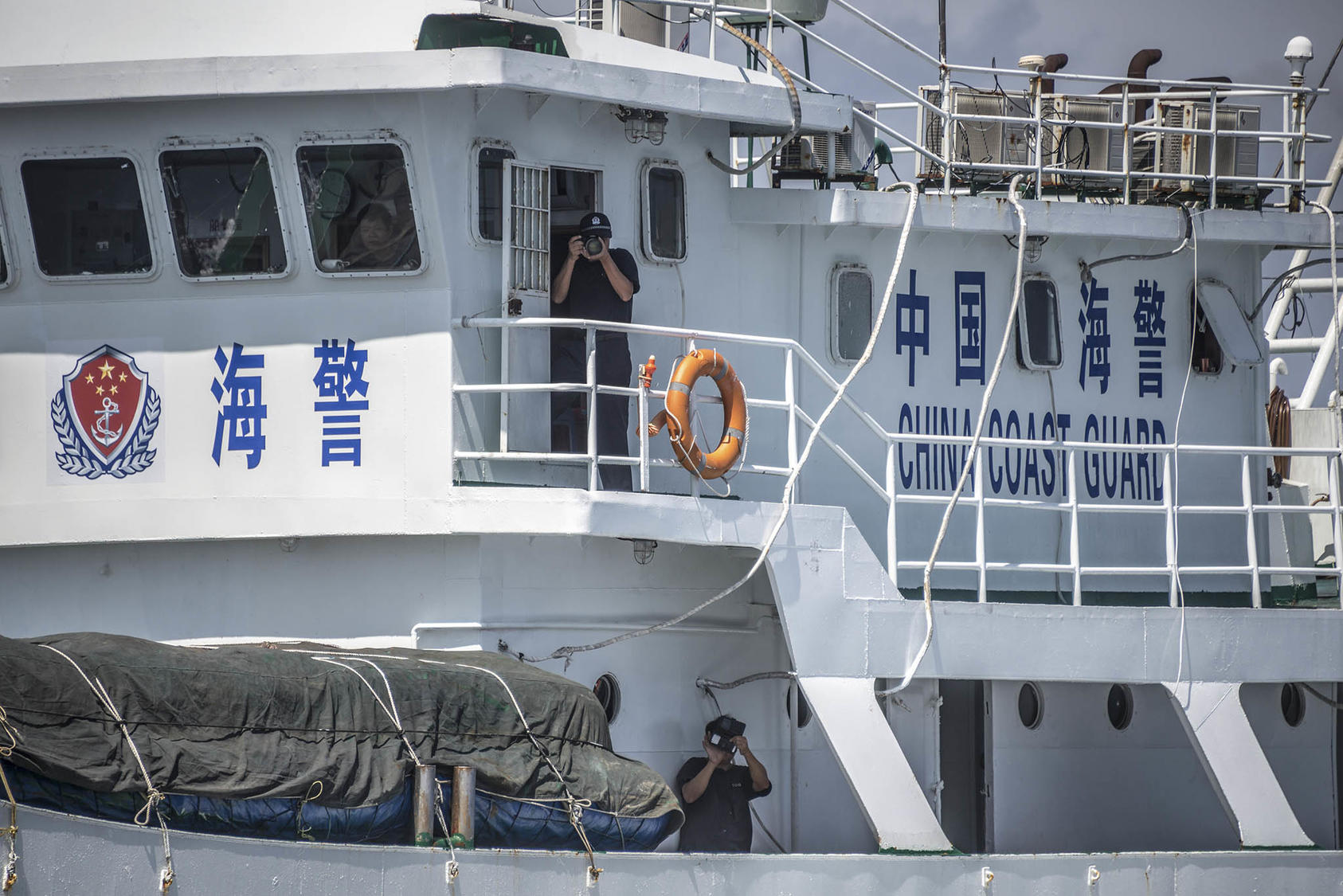 The crew of a Chinese Coast Guard ship photographs a Philippines commercial tour boat in the area of the Scarborough Shoal in the South China Sea, June 18, 2016. (Sergey Ponomarev/The New York Times)