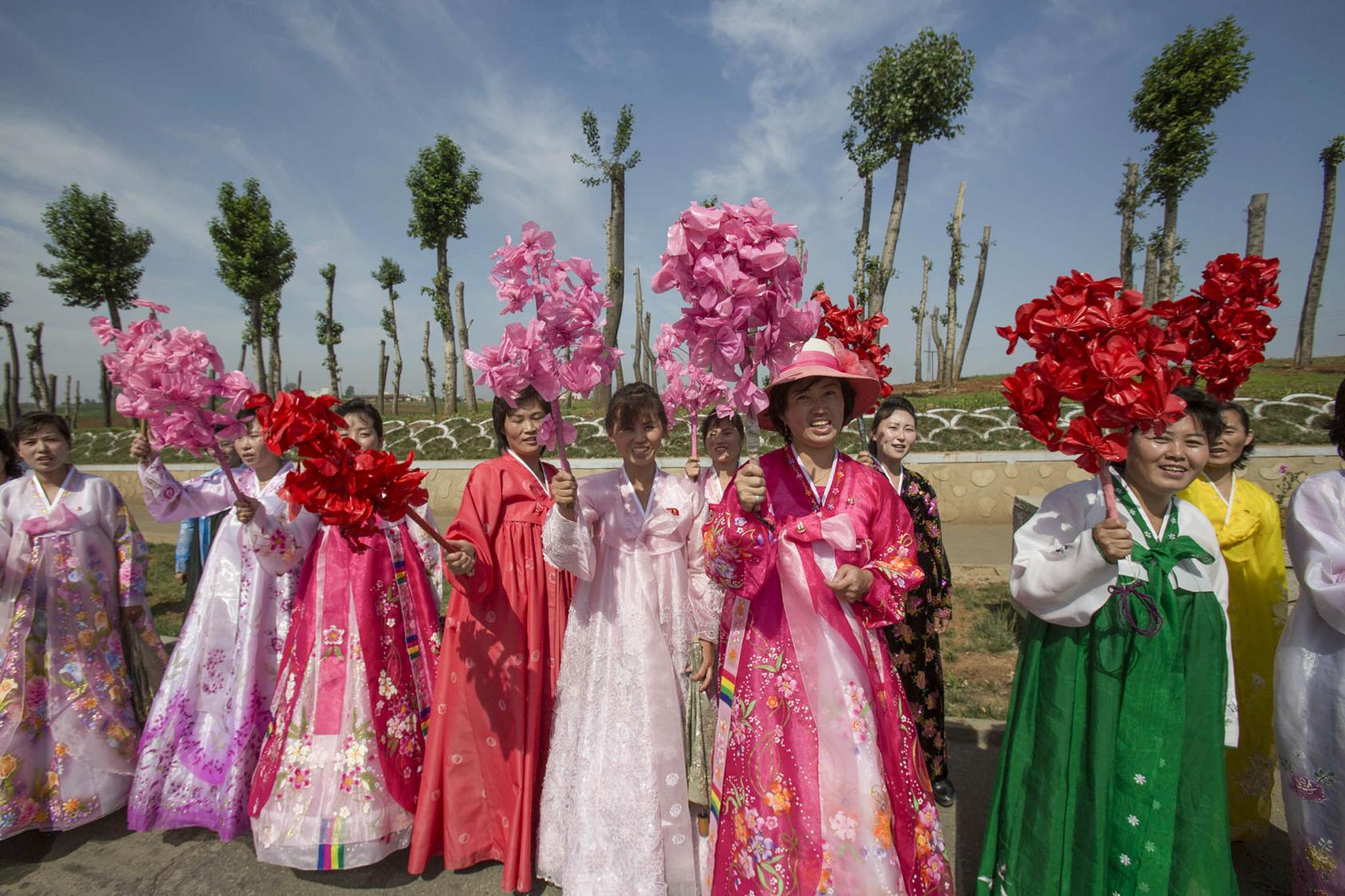 Women waved artificial flower bouquets as a group of activists passed during their rally calling for peace and reunification in Pyongyang, North Korea, May 22, 2015. (David Guttenfelder/The New York Times)