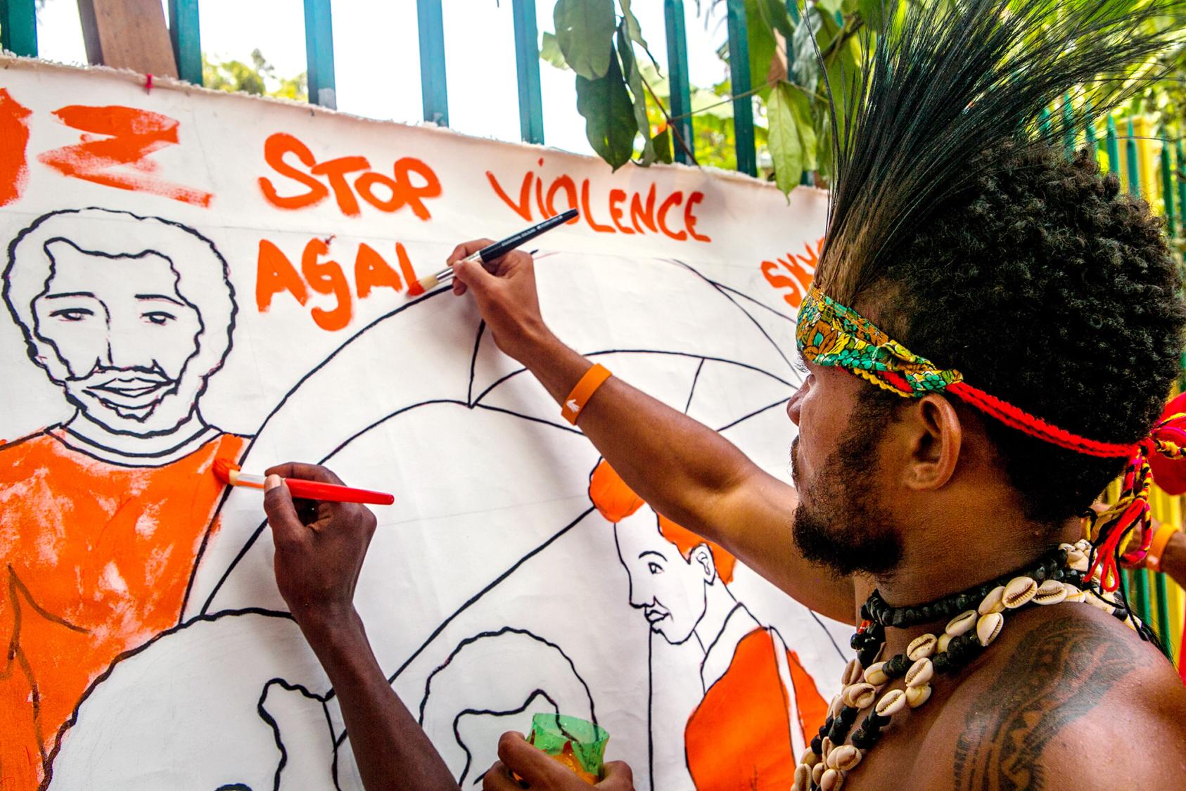 A man paints a sign to raise awareness of the "Orange the World" campaign to end violence against women and girls.