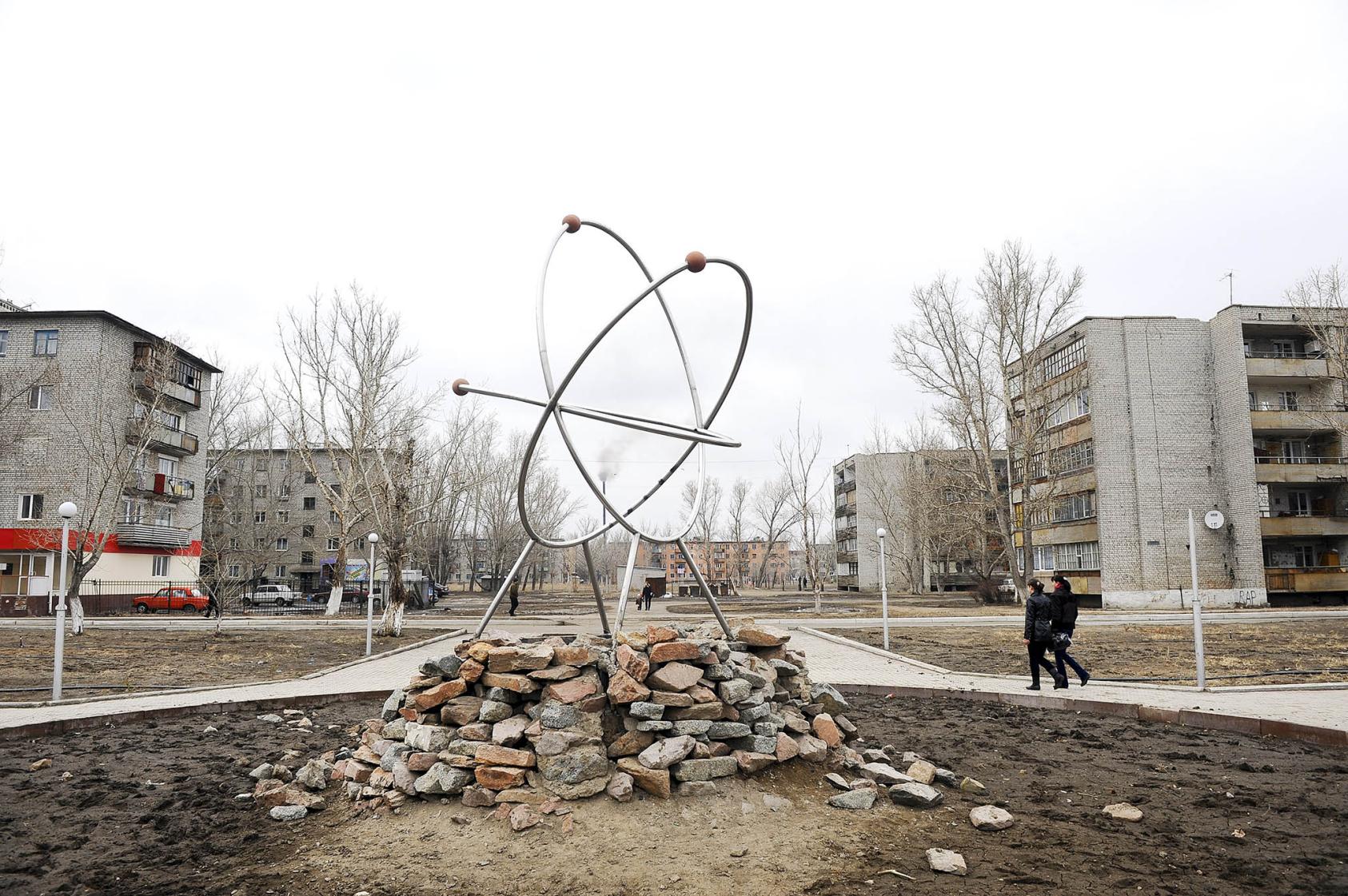 People walk by a sculpture of an atom near a region where the Soviet Union abandoned nuclear components and testing sites, in Kurchatov, Kazakhstan, April 2, 2011. (James Hill/The New York Times)