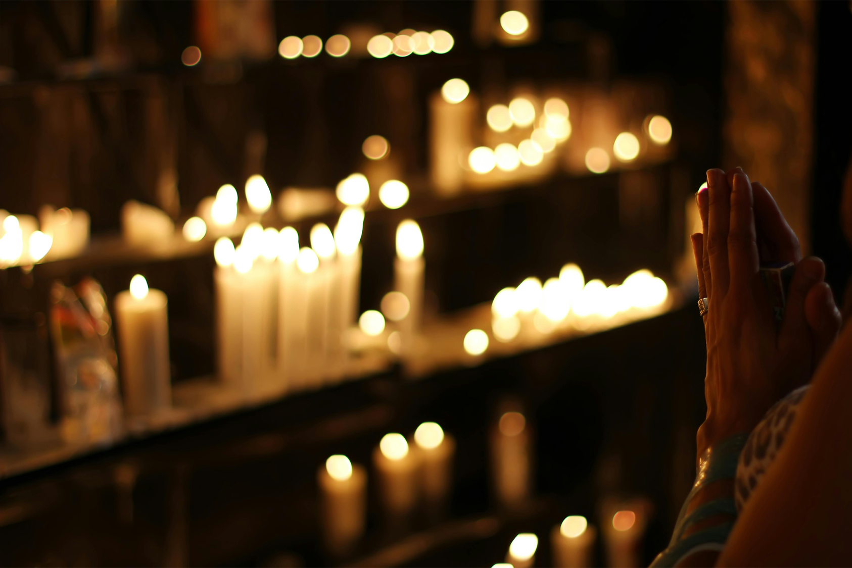 Photograph of Person Praying in Front Lined Candles (Rodolfo Clix/Pexels)