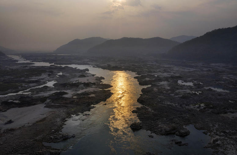 A narrowed Mekong River flows through the center of its partially dried out riverbed near Sangkhom, Thailand. January 25, 2020. (Adam Dean/The New York Times)