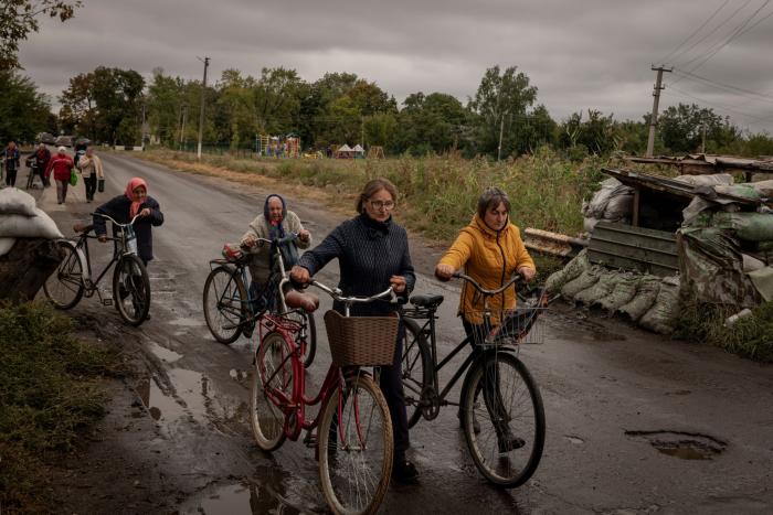 Women walk their bicycles past a checkpoint that had been set up by occupying Russian forces in the recaptured village of Verbivka, Ukraine, on Tuesday, Sept. 13, 2022. (Nicole Tung/The New York Times)